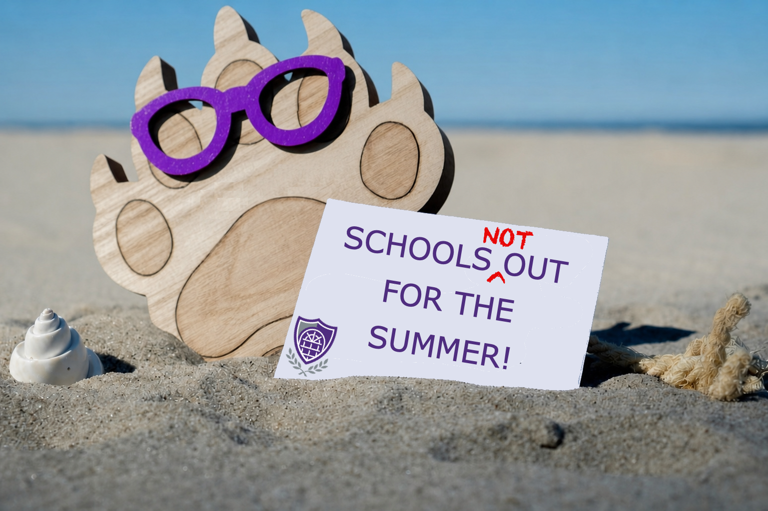 Bear paw with purple sunglasses and sign reading Schools not out for the summer on a sandy beach.