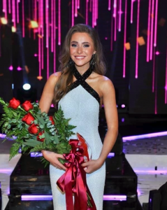 Kennedy Holland standing with flowers on stage.