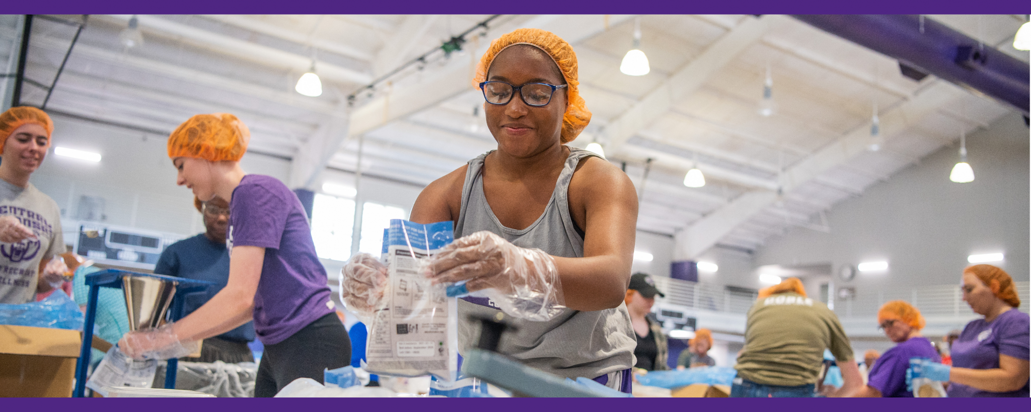 Students volunteer their time at a meal pack event on campus