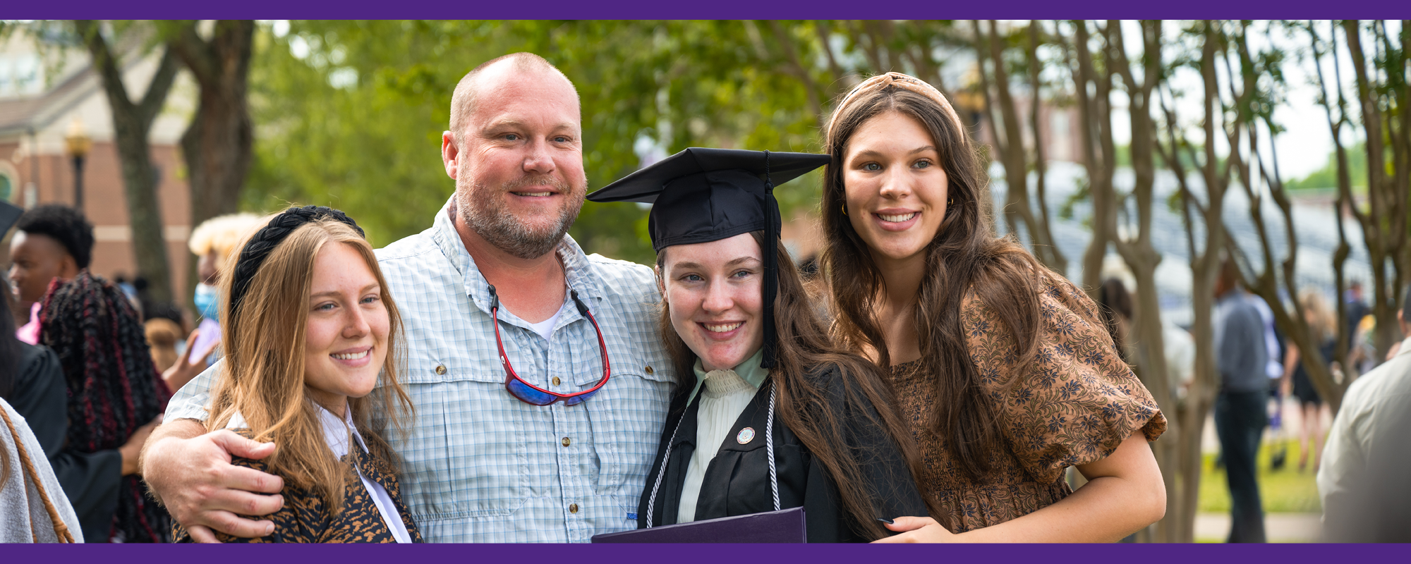 Father posing proudly with her daughter who is graduating